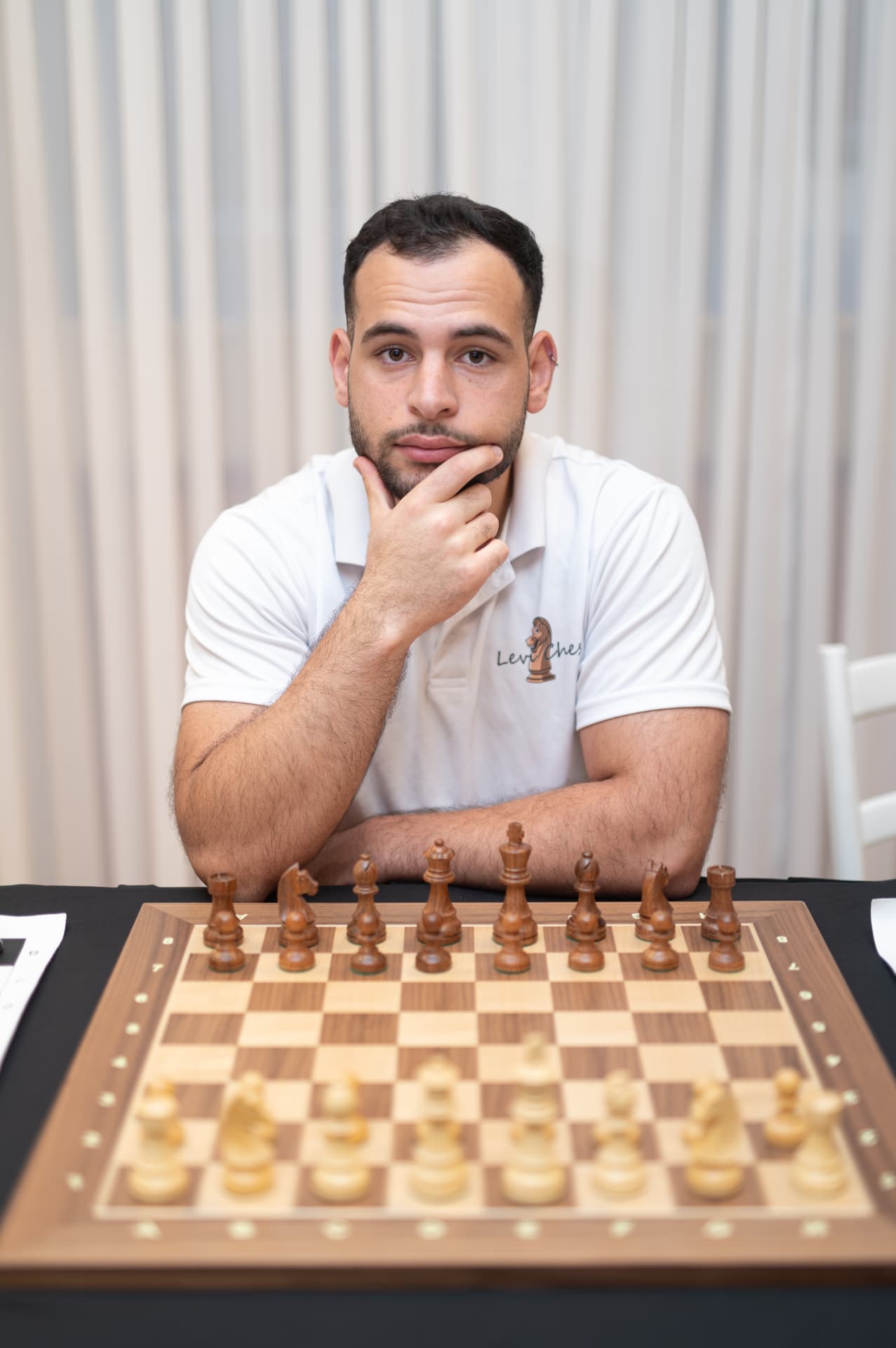 מאמן השחמט והיוצר של שחמטלנד יושב מול לוח שחמט